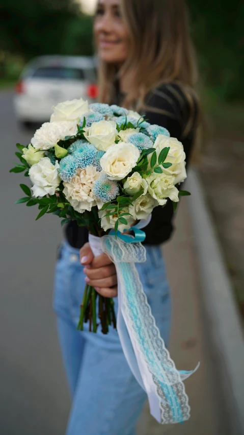 a woman in jeans holding a bouquet of flowers