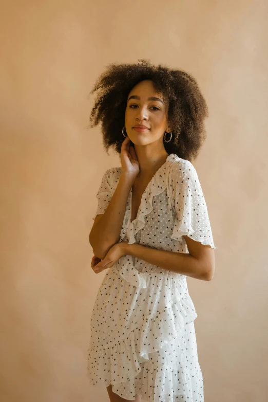 a woman with an afro standing in front of a beige wall