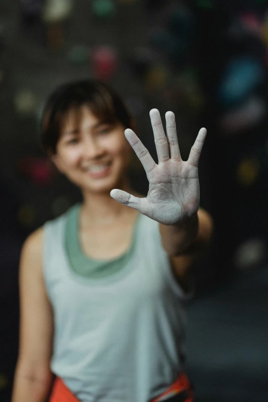 a woman shows her hand and looks at the camera