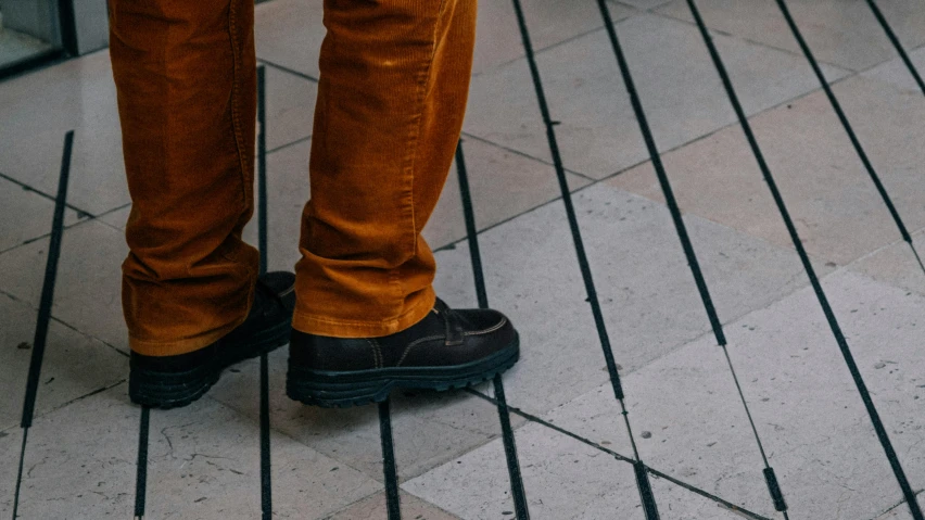 a person standing in brown pants and black shoes