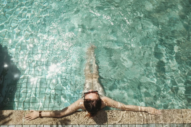 a woman is swimming in a pool near the water