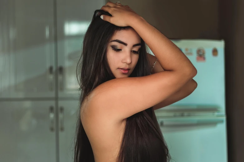 a woman in the kitchen holding her hair back