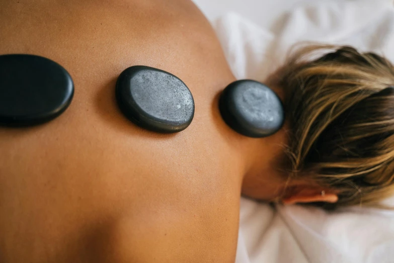 the back of a person in a bed with  stone massage