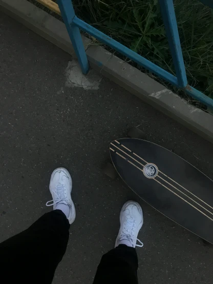 a person is standing next to a skateboard in a parking lot