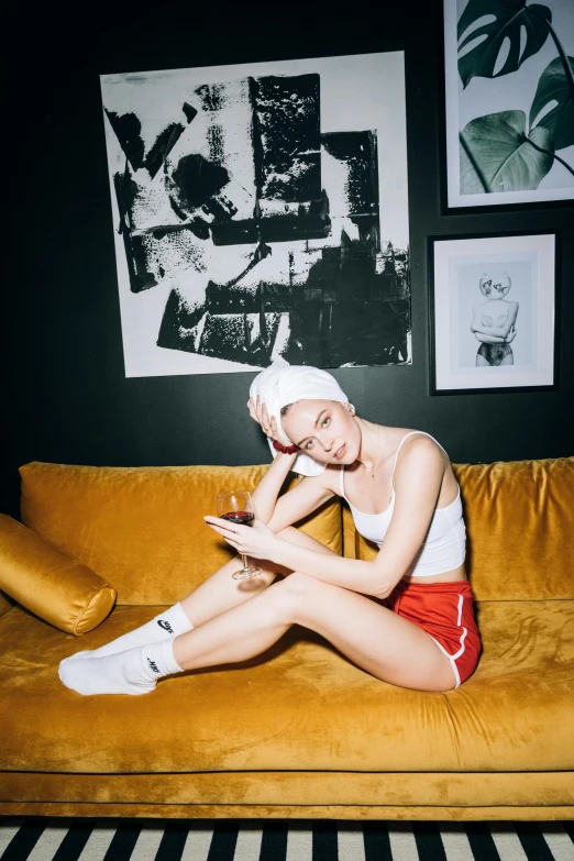 a woman is sitting on a yellow couch while using her laptop