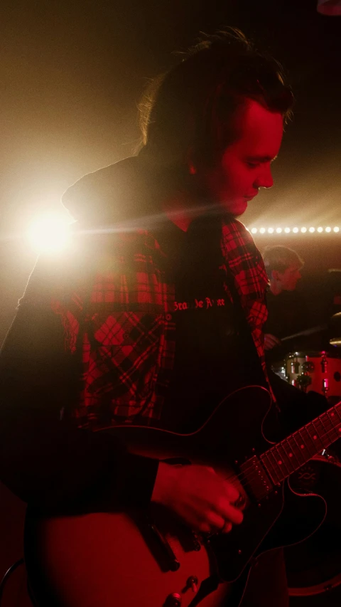 a man playing a guitar while standing next to a microphone