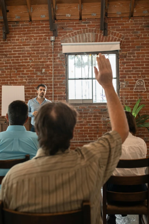 man raising hand to speak in front of audience