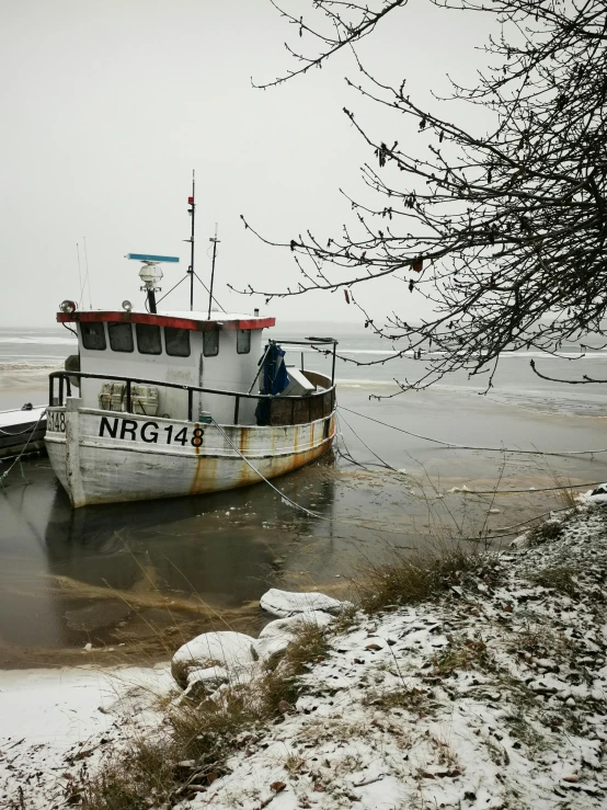 a fishing boat docked at an ice covered shore