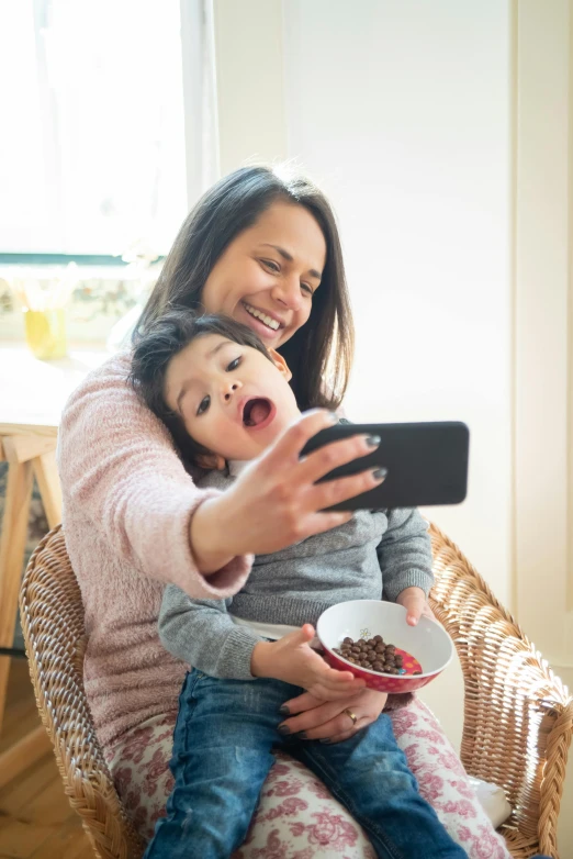 a woman is holding her son who has food in their lap