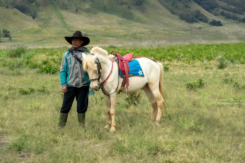 a man in cowboy hat standing with a white horse