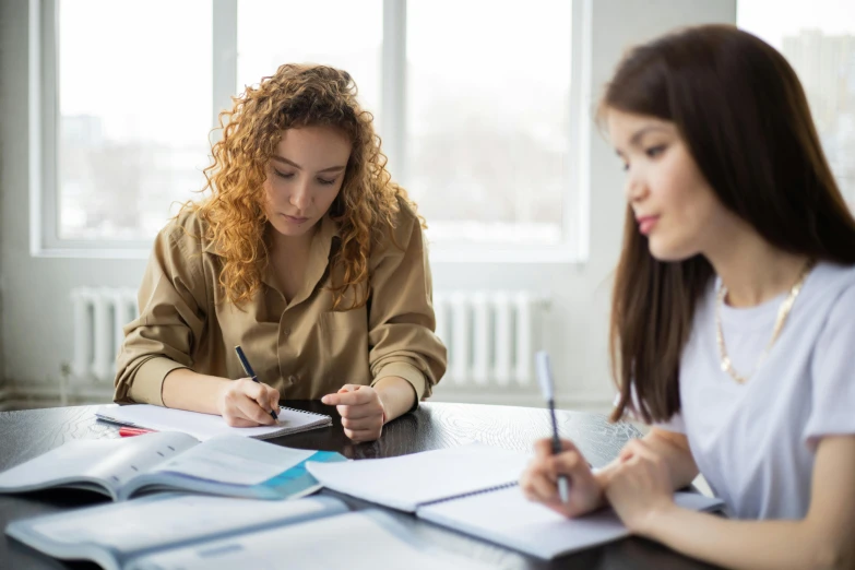 two girls sitting at a table and writing