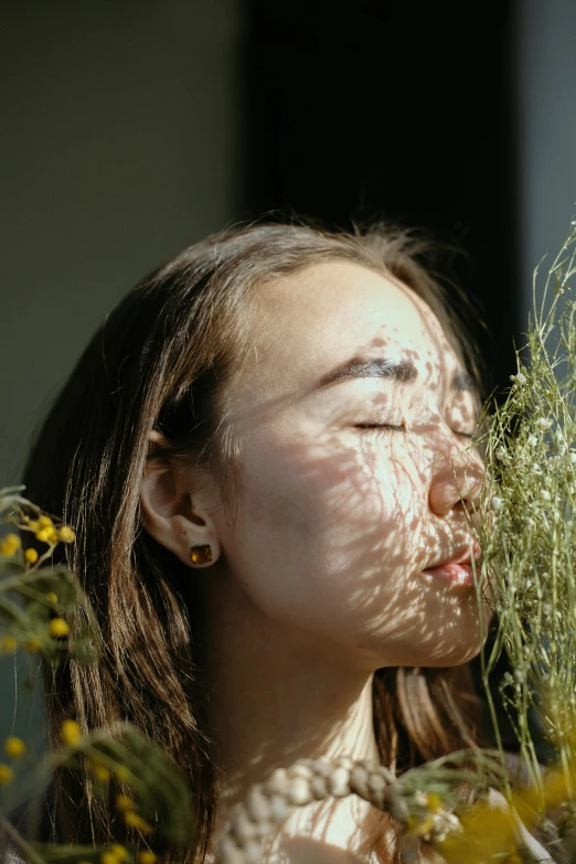 the girl is smelling the flowers outside