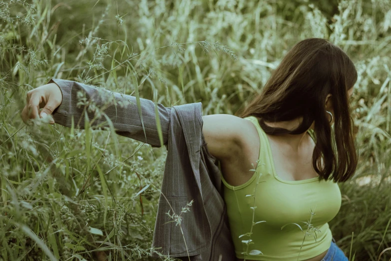 a young woman crouching down in some tall grass