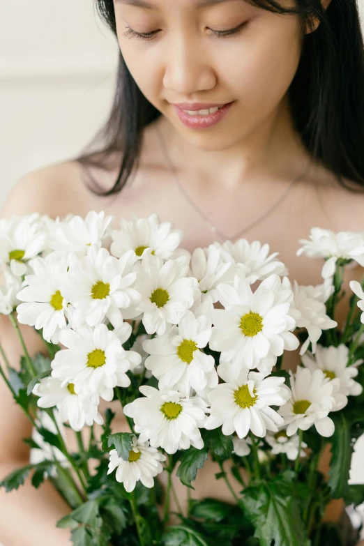 the girl is holding a bunch of white flowers