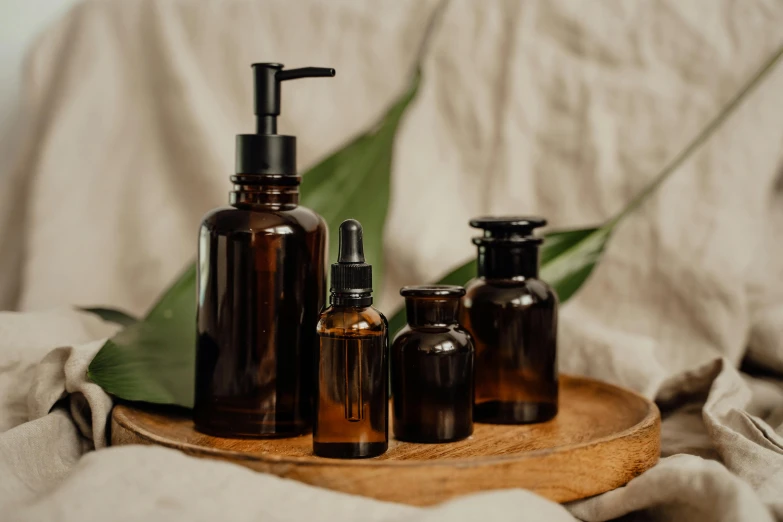 five bottles of essential soap sit on a wooden tray