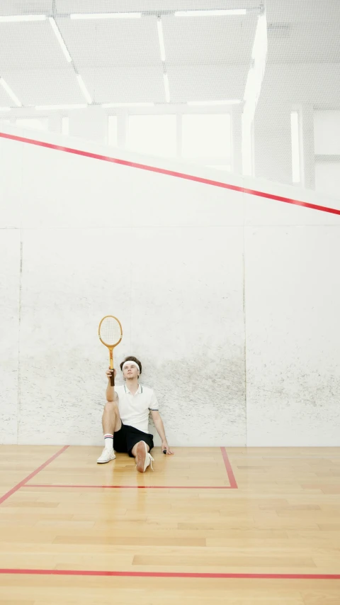 a man is on the floor holding a racket