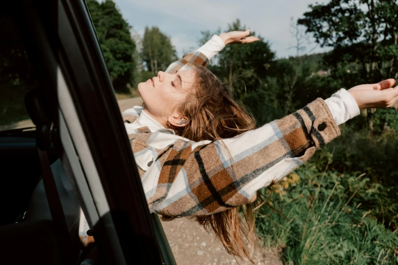 woman's hand extended out from car window, reaching up at viewer