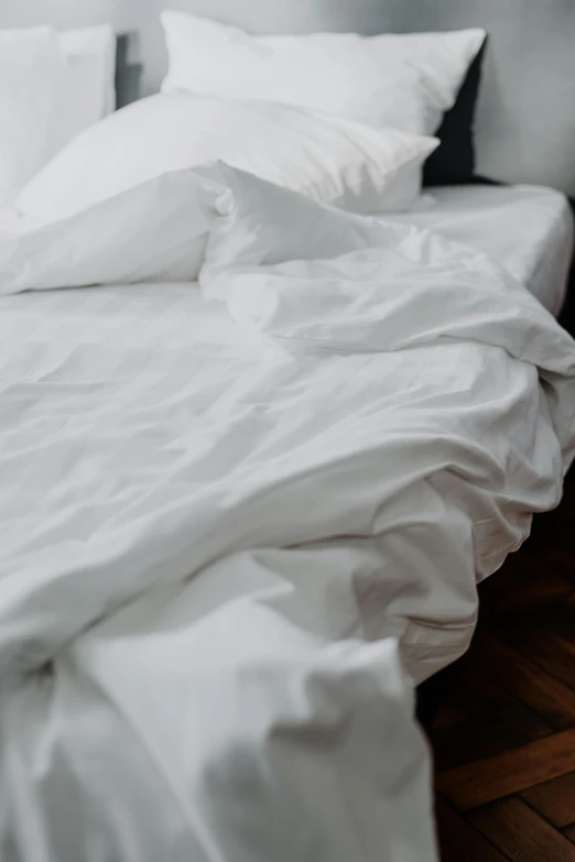 white sheets and pillowcases are on top of a bed