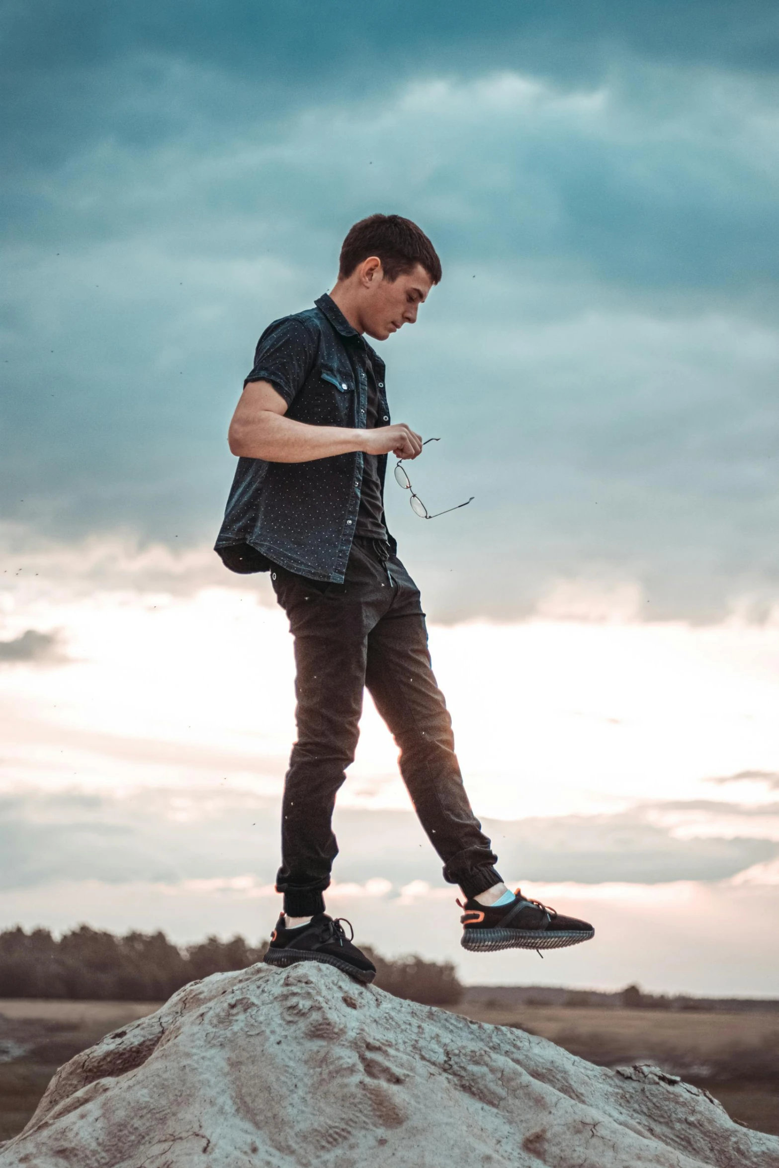 there is a male in a black shirt and pants on a hill with snowballs