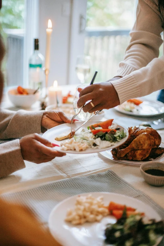 people are standing at a table with white plates with food