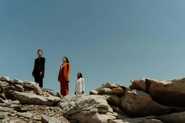 three people standing on top of a rock outcropping