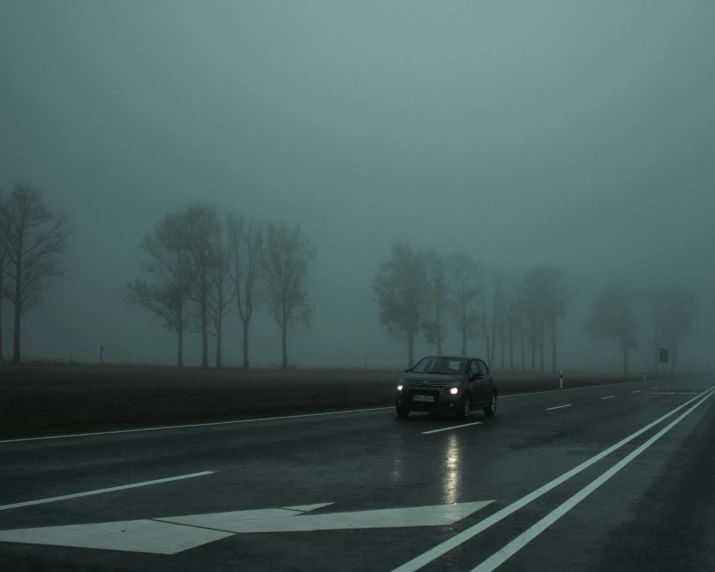 a car parked on a wet road in the middle of fog