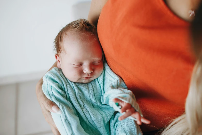 an adult holds a sleeping baby in her arms