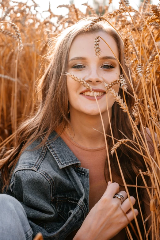 a woman smiling as she stands in tall grass