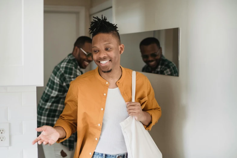 man in yellow jacket carrying bag while smiling in mirror