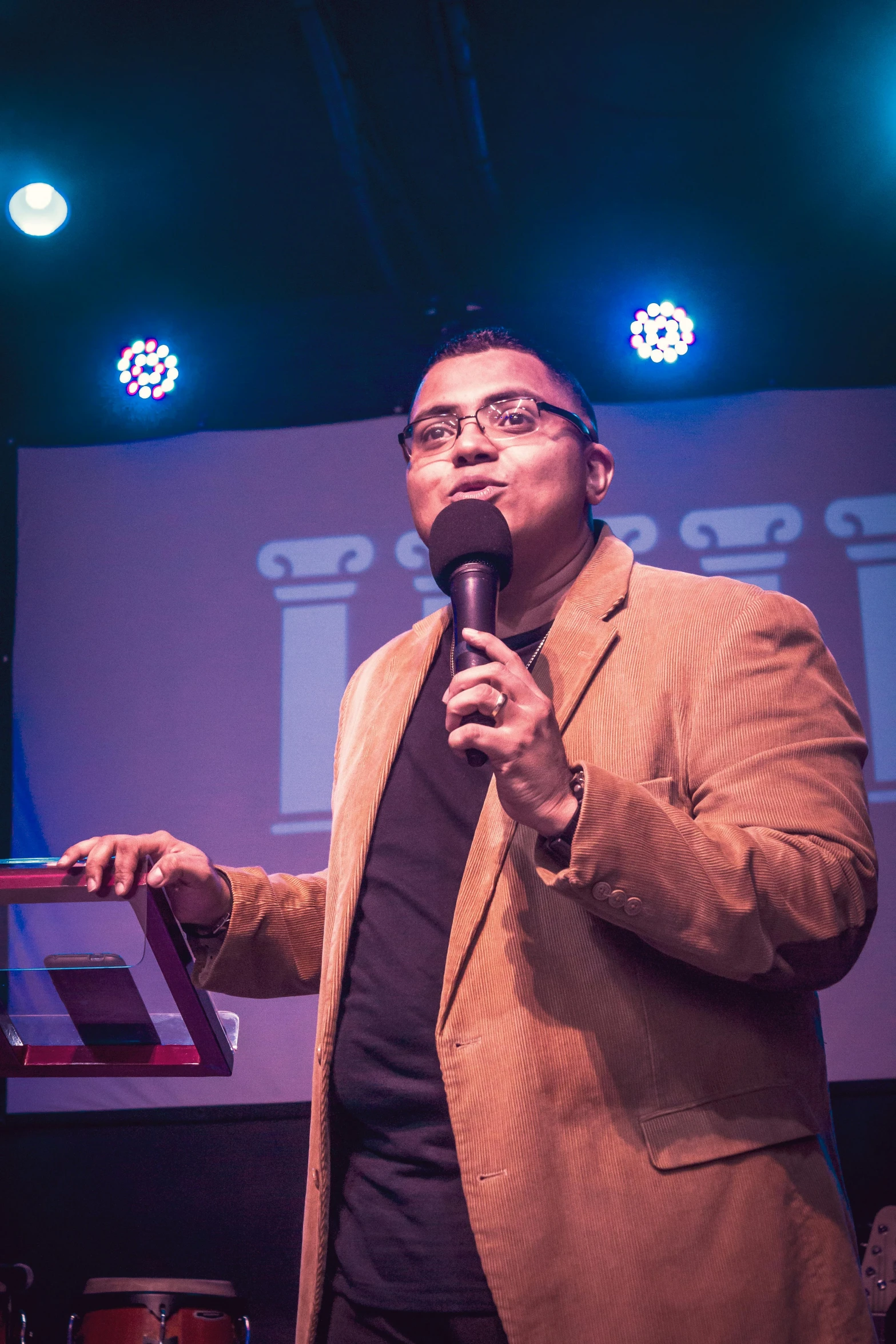 a man standing on stage talking into a microphone