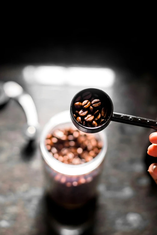 a spoon is holding a bowl filled with coffee beans