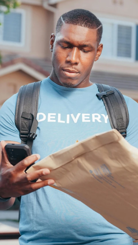a man holding a delivery box is looking at a piece of cardboard