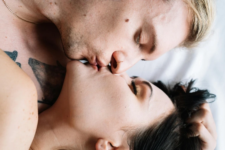 two people laying in bed making a heart with their nose