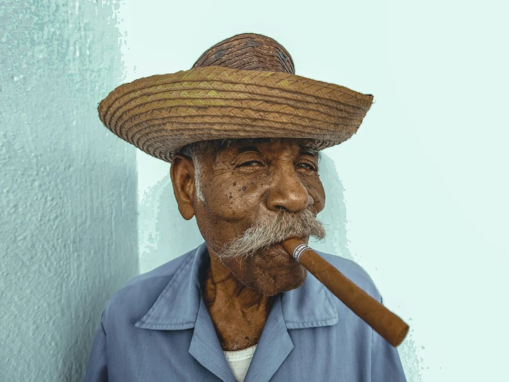 a man with a hat on and a cigarette in his mouth