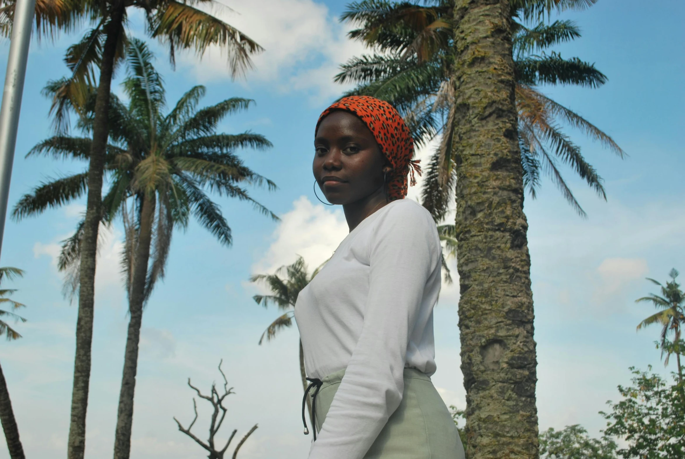 a woman is standing near the palm trees