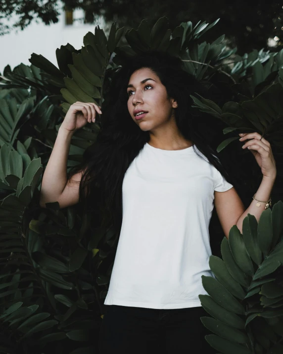 a woman standing next to a bush filled with leaves