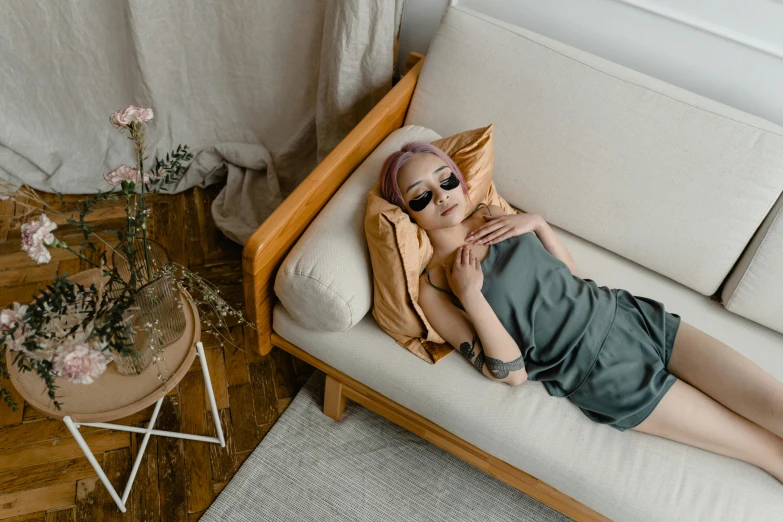 a woman laying on a couch next to flowers