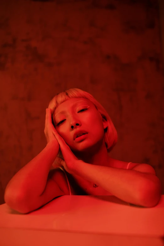 woman in red dress leaning over bed with her hands on her head