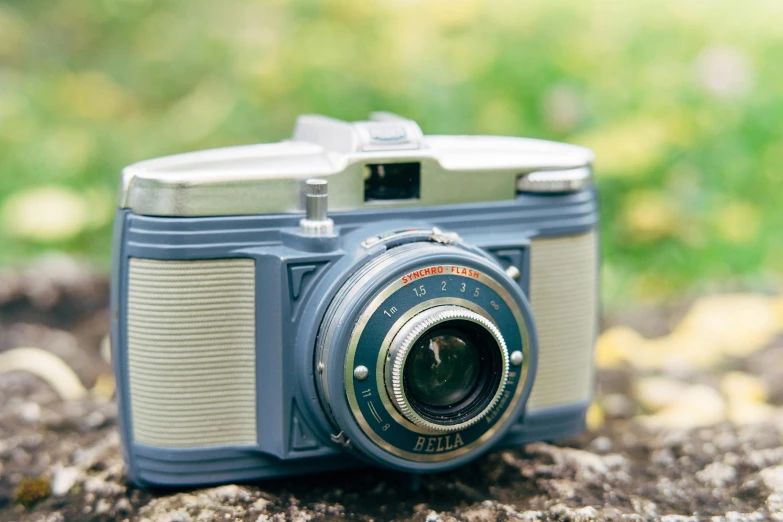 an old, blue and gray camera sitting on top of a rock