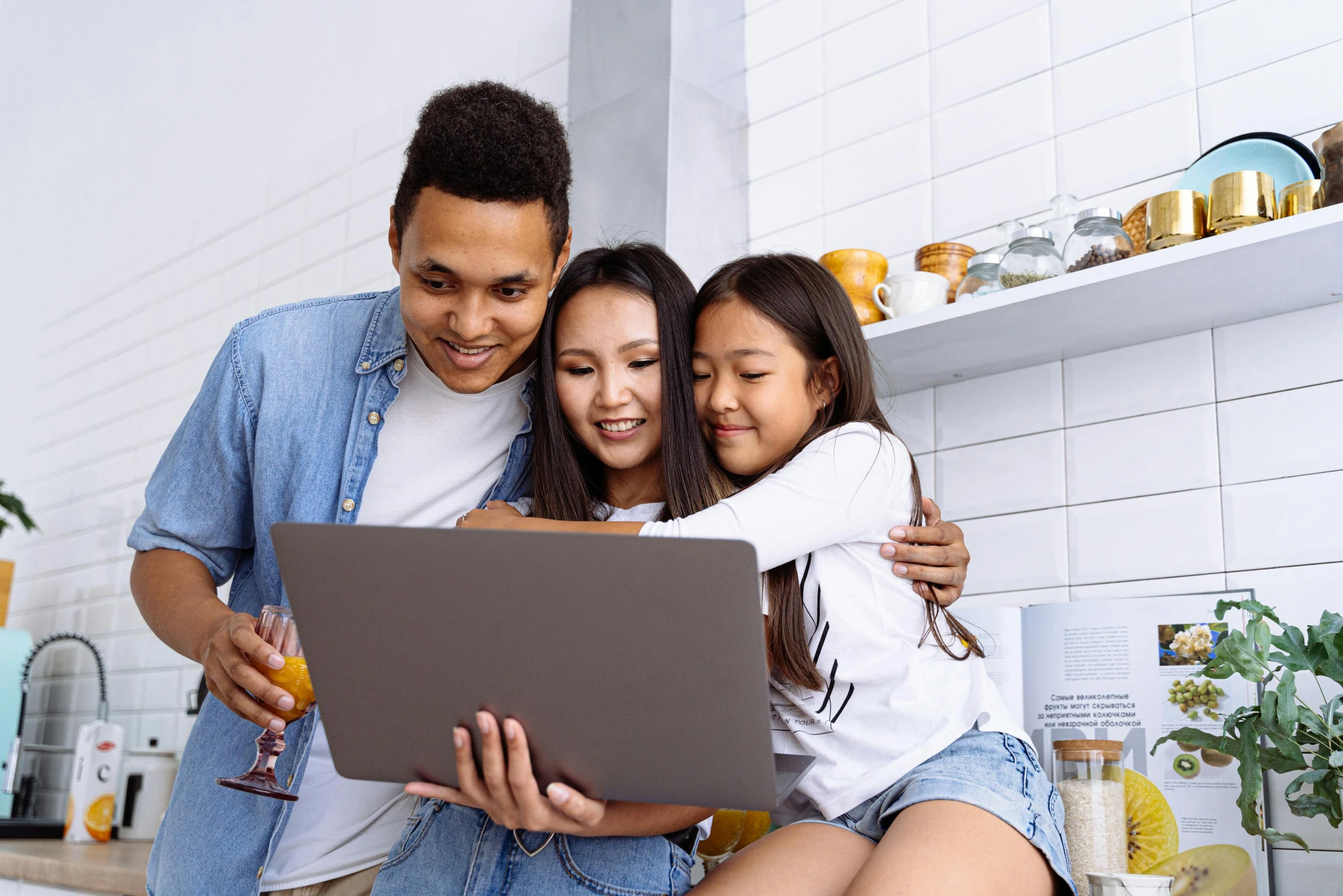 two people sitting on a kitchen counter and using a laptop