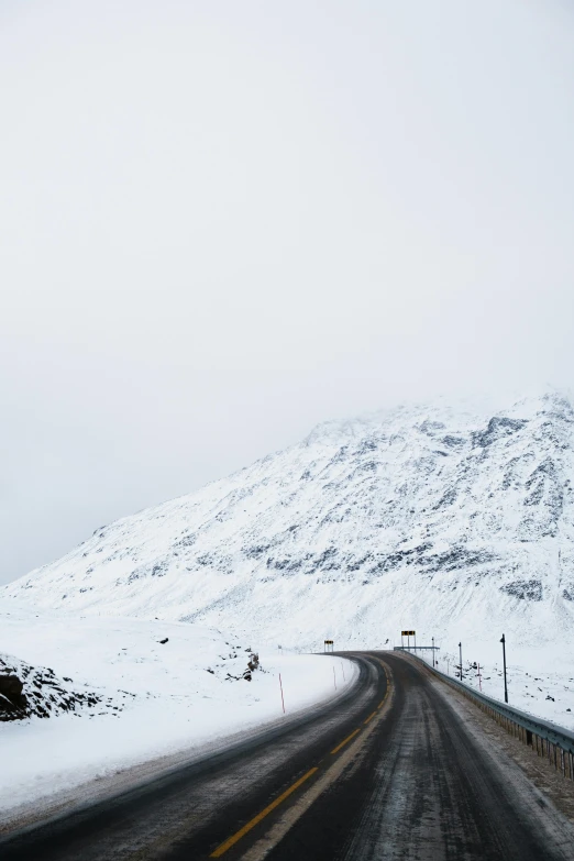 a snowy mountain and road with light traffic going through