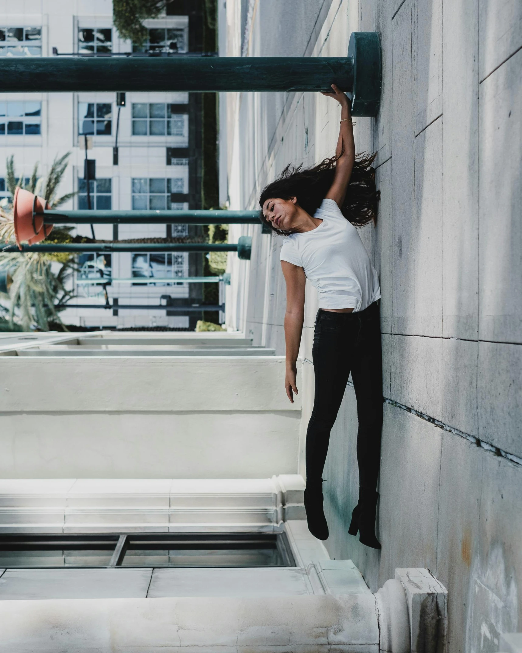 a woman hanging upside down on a building near some stairs