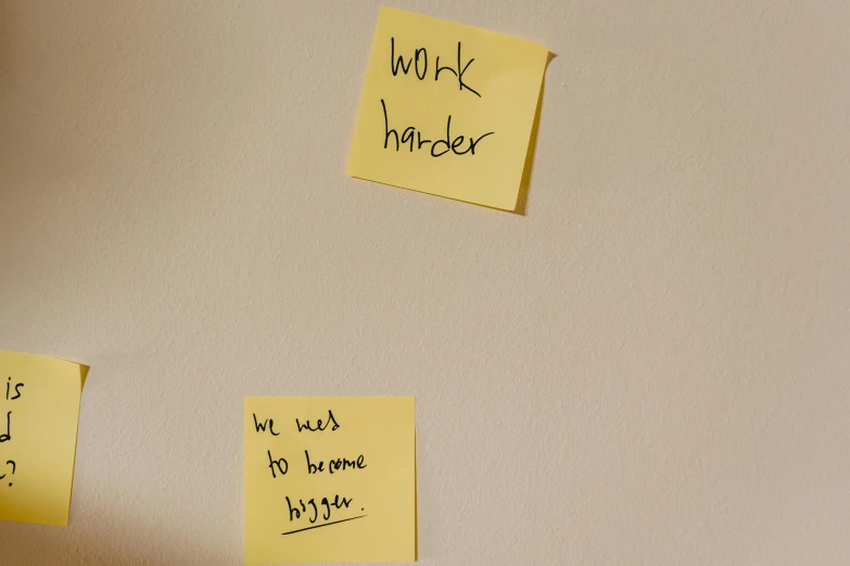 sticky notes posted to the wall that say work harder
