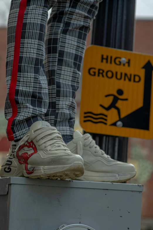 the legs of someone with sneakers on near a ground sign