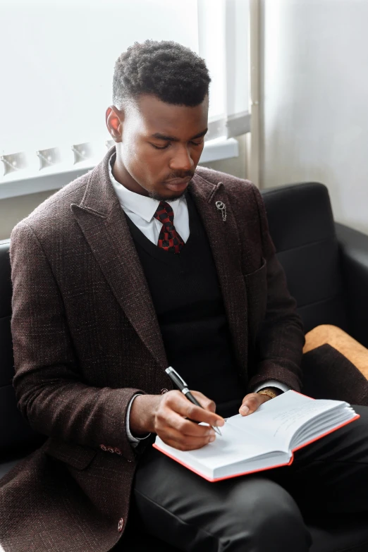 a young man in suit and tie writing in a notebook