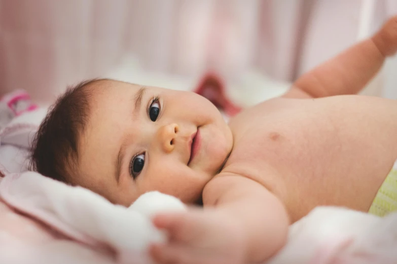 a baby with large eyes lies in a crib