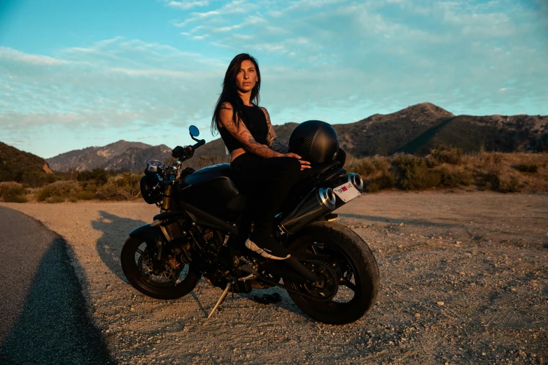 a woman is sitting on a motorcycle in the desert