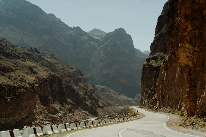 a winding mountain road runs next to the mountains