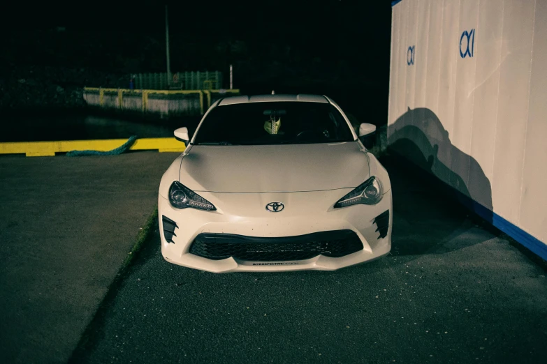 a white toyota car parked in front of a blue and white container