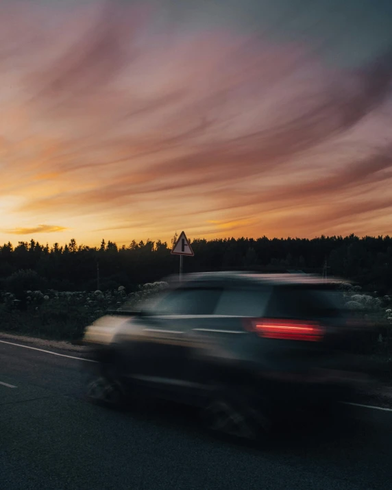 a car driving down the road with sunset in background